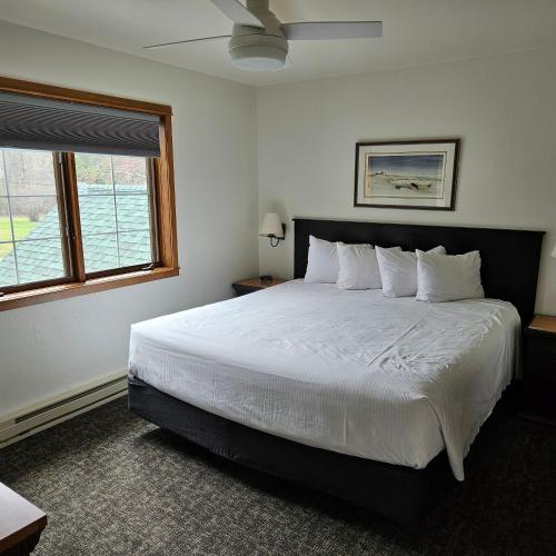 a bedroom with a large bed with white sheets and a window at Homestead Suites - Fish Creek in Fish Creek