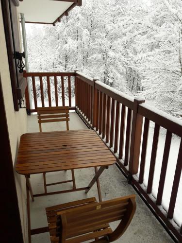 un balcon avec un banc en bois et des arbres enneigés dans l'établissement Appartement 2 chambres au pied des pistes de l'espace Diamant, à Flumet