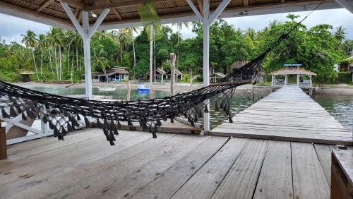 a hammock on a dock on a body of water at Pristine Paradise Dive Resort - Togean Islands, Una Una in Pulau Unauna