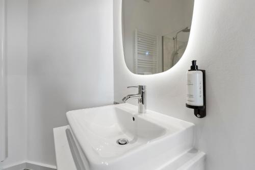 a white bathroom with a sink and a mirror at sgrafit apartments - Self Check-In in Retz