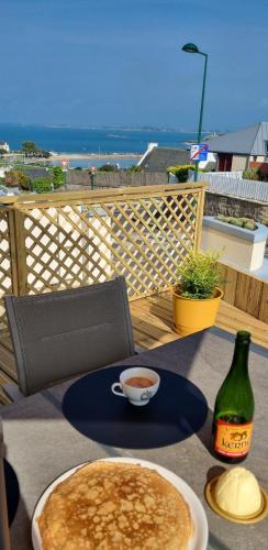 une table avec une assiette de crêpes et une tasse de café dans l'établissement Maison vue mer LES 4 VAGUES, à Saint-Pol-de-Léon