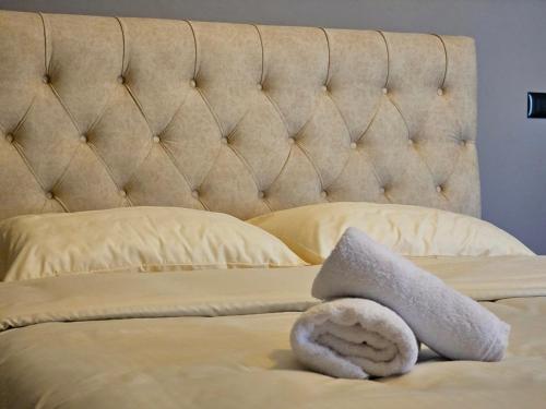 a bed with a tufted headboard with a white towel at Hani i Ilirit in Cërrik