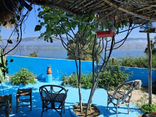 a table with chairs and a tree in front of a blue wall at Maison d'hotes oued el Makhazine chez Bilal in Mimouna