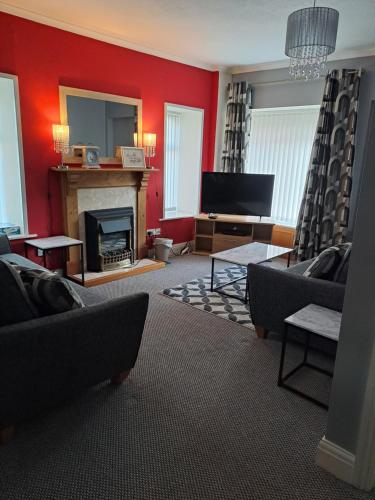 a living room with red walls and a fireplace at 94 Main Street - Pembroke Holiday Home in Pembroke
