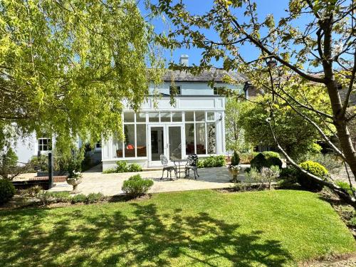 a white house with a patio and a yard at Stunning and luxurious Manor House holiday home in Broadmayne