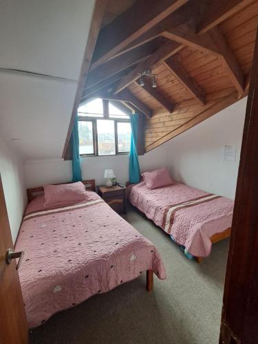 a bedroom with two beds and a window at Hostal Valentino in Villarrica