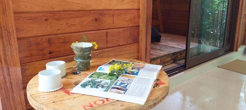 a wooden table with a magazine and a book on it at Cabana de madeira entre as árvores in Piedade