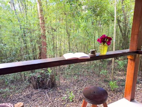 a table with a book and a vase of flowers at Cabana de madeira entre as árvores in Piedade