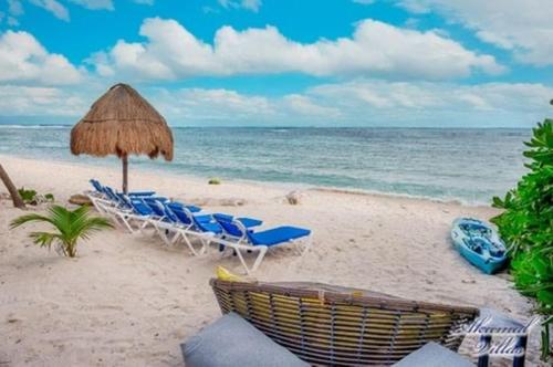 a group of chairs and an umbrella on a beach at Beachfront Hammock Heaven in Akumal