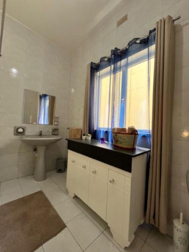 a white bathroom with a sink and a window at Carmax 2 Bedroom Appartment Birzebbugia in Birżebbuġa