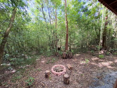 a garden with a wheel in the middle of a forest at Cabana de madeira entre as árvores in Piedade