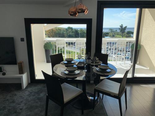une salle à manger avec une table et des chaises et un balcon dans l'établissement Loft vue Bassin Arcachon Marina de Cassy, à Lanton