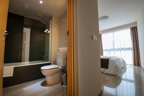 a bathroom with a toilet and a bed and a tub at Apartaments Peronel.la in Lleida