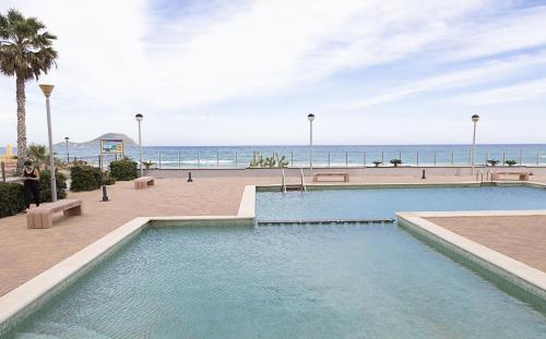 a swimming pool with the ocean in the background at Costa Azul 5 L in La Manga del Mar Menor