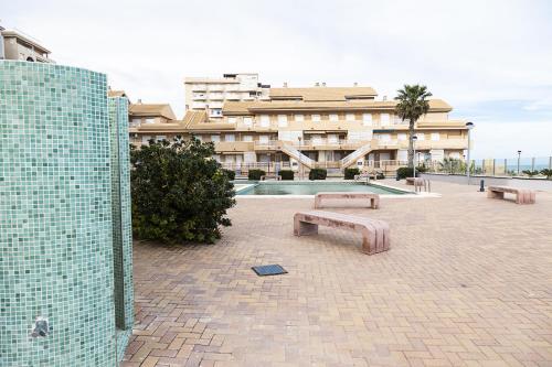 a building with a pool and benches in a courtyard at Costa Azul 5 L in La Manga del Mar Menor