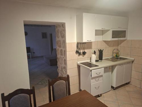a kitchen with white cabinets and a table and chairs at Forteca home in Perast