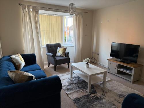 a living room with a blue couch and a tv at Bunting Haven in Corby
