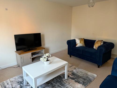 a living room with a blue couch and a tv at Bunting Haven in Corby