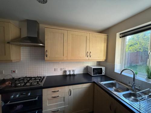 a kitchen with a stove and a sink and a window at Bunting Haven in Corby