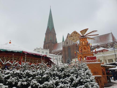 a christmas market with snow covered trees and a church at Neumühler Hof- Gemütliche Wohnung "Lenia" Parkplätze und Kongresshalle in der Nähe in Schwerin