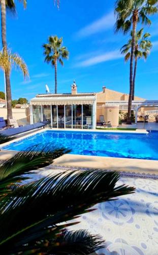 a swimming pool with palm trees and a house at Casa Valdi, fantastic 4 bedroom house with private,heated swimming pool and barbecue in Ciudad Quesada