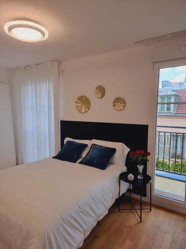 une chambre avec un grand lit blanc et une fenêtre dans l'établissement Appartement neuf et moderne à Puteaux, à Puteaux