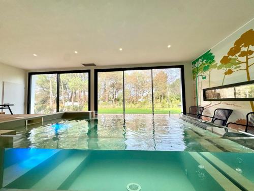- une piscine dans une maison avec une grande fenêtre dans l'établissement Villa neuve Piscine intérieure 18pers, à Gujan-Mestras