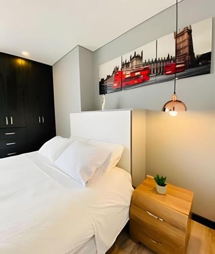 a bedroom with a white bed and a painting on the wall at Domus Suites Chia in Chía