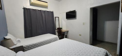a hotel room with two beds and a television at Casa Altamira in San Pedro Sula