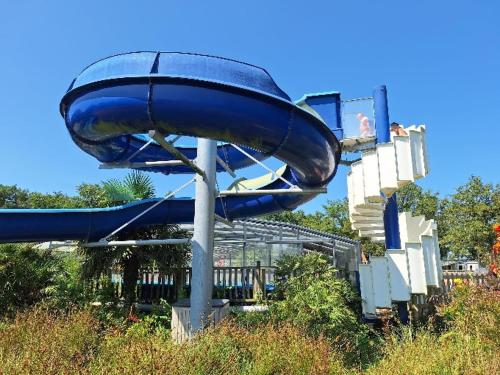 un toboggan bleu dans une aire de jeux avec des gens dessus dans l'établissement Mobil-home en pleine Nature, à La Boissière-de-Montaigu