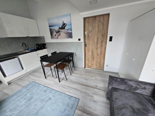 a kitchen and dining room with a table and a door at Apartament Patio Antresol 2 Świnoujście in Świnoujście