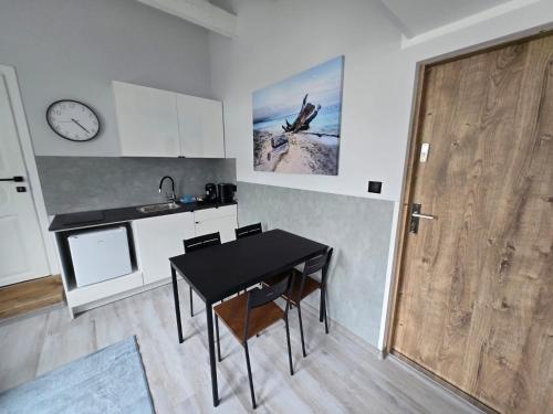 a kitchen with a table and a clock on the wall at Apartament Patio Antresol 2 Świnoujście in Świnoujście