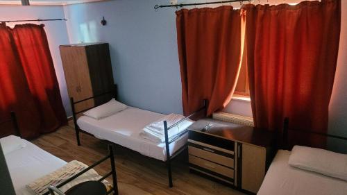 a small room with two beds and red curtains at Byzanthin Hostel in Bucharest