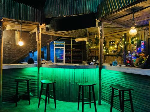 Una barra verde con taburetes delante. en Ella Forest Bath, en Ella