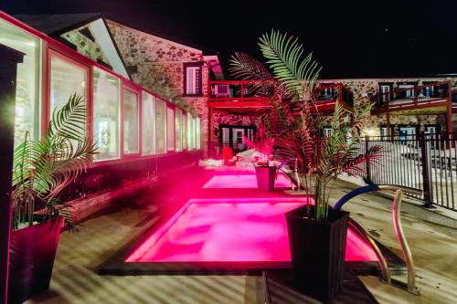Una piscina con luces rosas en un edificio con plantas. en Condo Hôtel Magog Orford, en Orford