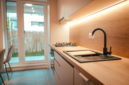eine Küche mit einer Spüle, einem Herd und einem Fenster in der Unterkunft Modern Apartment Atria Urban - North Bucharest, Sector 1 in Bukarest