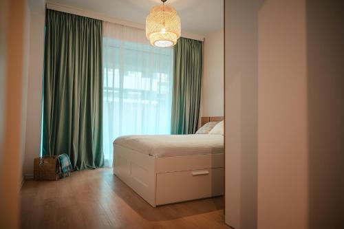 Schlafzimmer mit einem Bett und einem Fenster mit grünen Vorhängen in der Unterkunft Modern Apartment Atria Urban - North Bucharest, Sector 1 in Bukarest