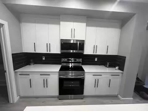 エドモントンにあるBrand New Bedroom with private bathroom in Keswickのキッチン(白いキャビネット、黒いコンロ付)