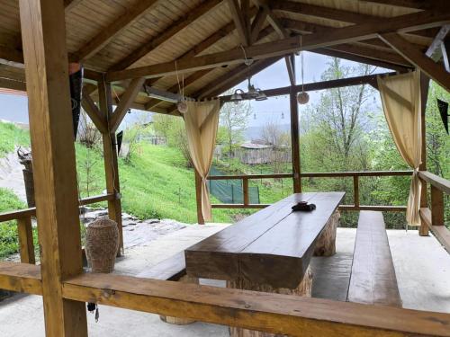 a wooden table in a pavilion with a view of a field at Cabana de lemn Lacul Bicaz in Hangul