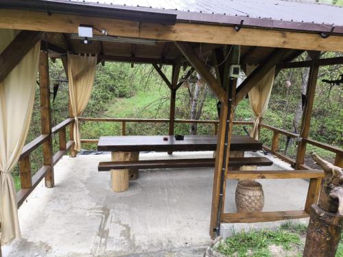 a wooden pavilion with a picnic table on a deck at Cabana de lemn Lacul Bicaz in Hangul