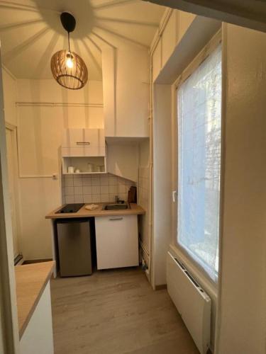 - une cuisine avec évier et une fenêtre dans la chambre dans l'établissement T2 cozy en centre-ville, à Montélimar