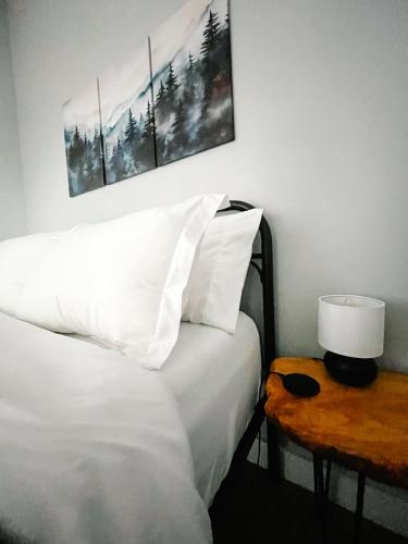 a bed with white pillows and a table with a lamp at Sooke Getaway - Relax & Recharge in Nature, Private 7min to Sooke in Sooke