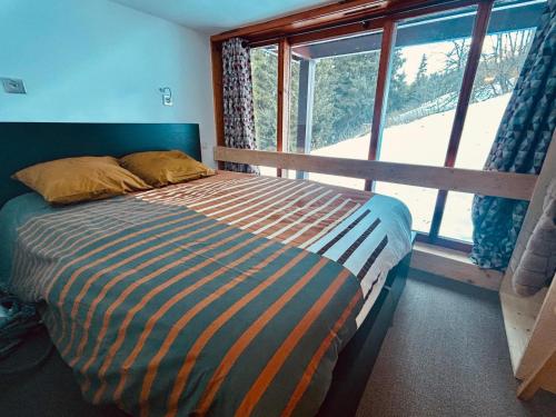 un lit dans une chambre avec une grande fenêtre dans l'établissement Appartement Les Arcs 1800 - Charmettoger, à Bourg-Saint-Maurice