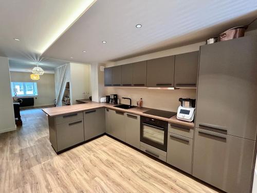 Il comprend une cuisine avec des appareils en acier inoxydable et du parquet. dans l'établissement Ferme rénovée dans la région des lacs du Jura, à Châtillon