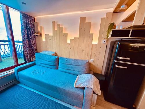 un canapé bleu dans une pièce avec une fenêtre dans l'établissement Appartement Les Arcs 1800 - Charmettoger, à Bourg-Saint-Maurice