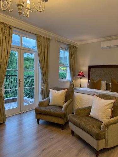 een slaapkamer met een bed, een bank en een stoel bij Franschoek Lermitage Villa 33 Three Bedroom Lake View in Franschhoek