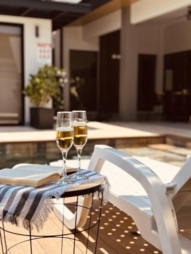 dos copas de vino sentadas en una mesa junto a una piscina en Casa Morfa, en Uvita