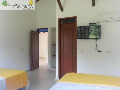 a bedroom with two beds and a tv on the wall at Finca Campestre Villa Andrea in Restrepo