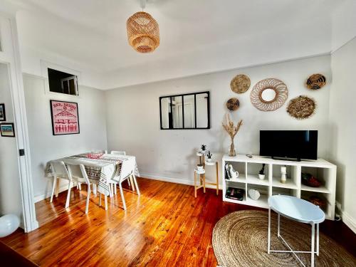 a living room with a table and chairs and a television at Appartement plein centre, lumineux et spacieux in Saint-Jean-de-Luz