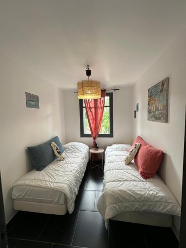 two beds in a room with a window at Home Cassis - Maison Les Calanques - Piscine chauffée à 30c in Cassis
